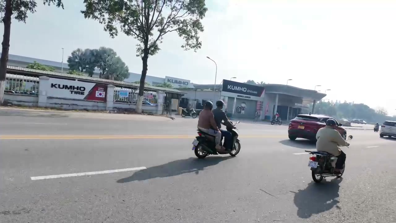 Nhà máy trong khu công nghiệp Mỹ Phước gần dãy trọ, công nhân chạy xe máy trên đường trước cổng