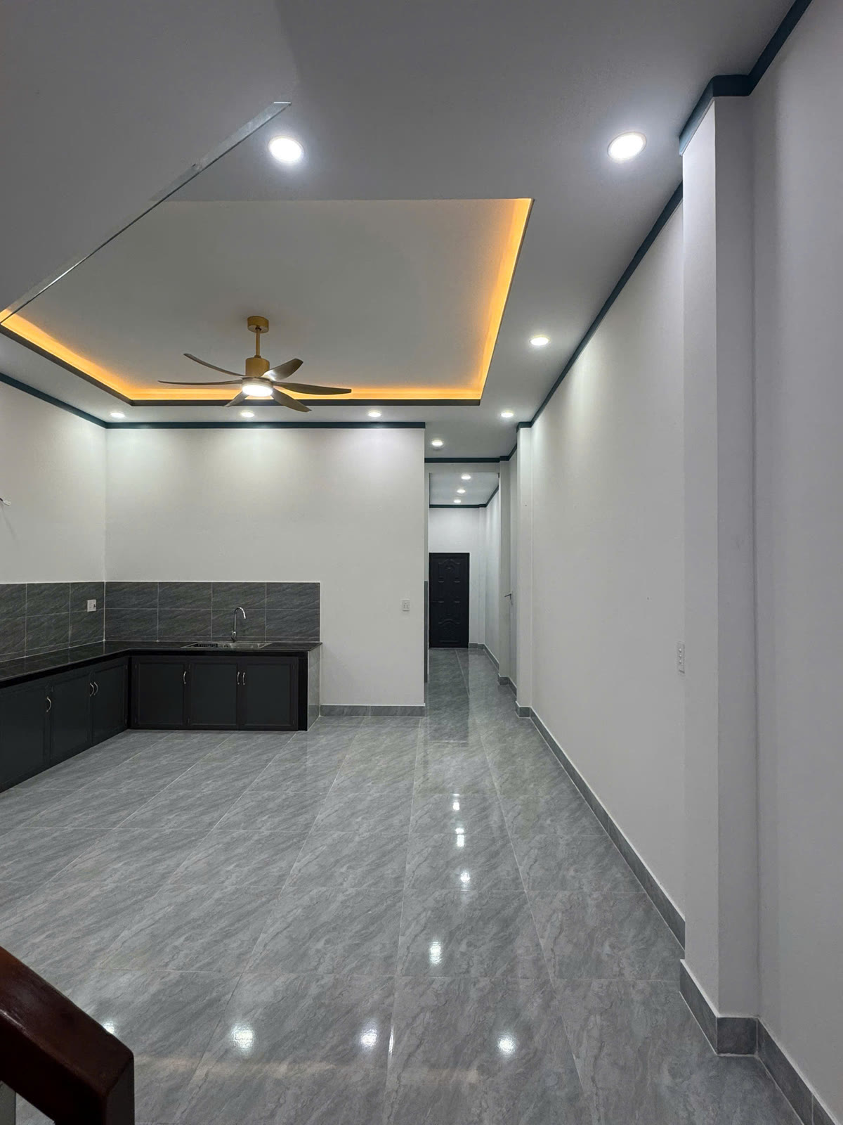 Bếp nhà lầu trệt 5x20 Mỹ Phước có tủ bếp dưới, tường ốp gạch và quạt trần