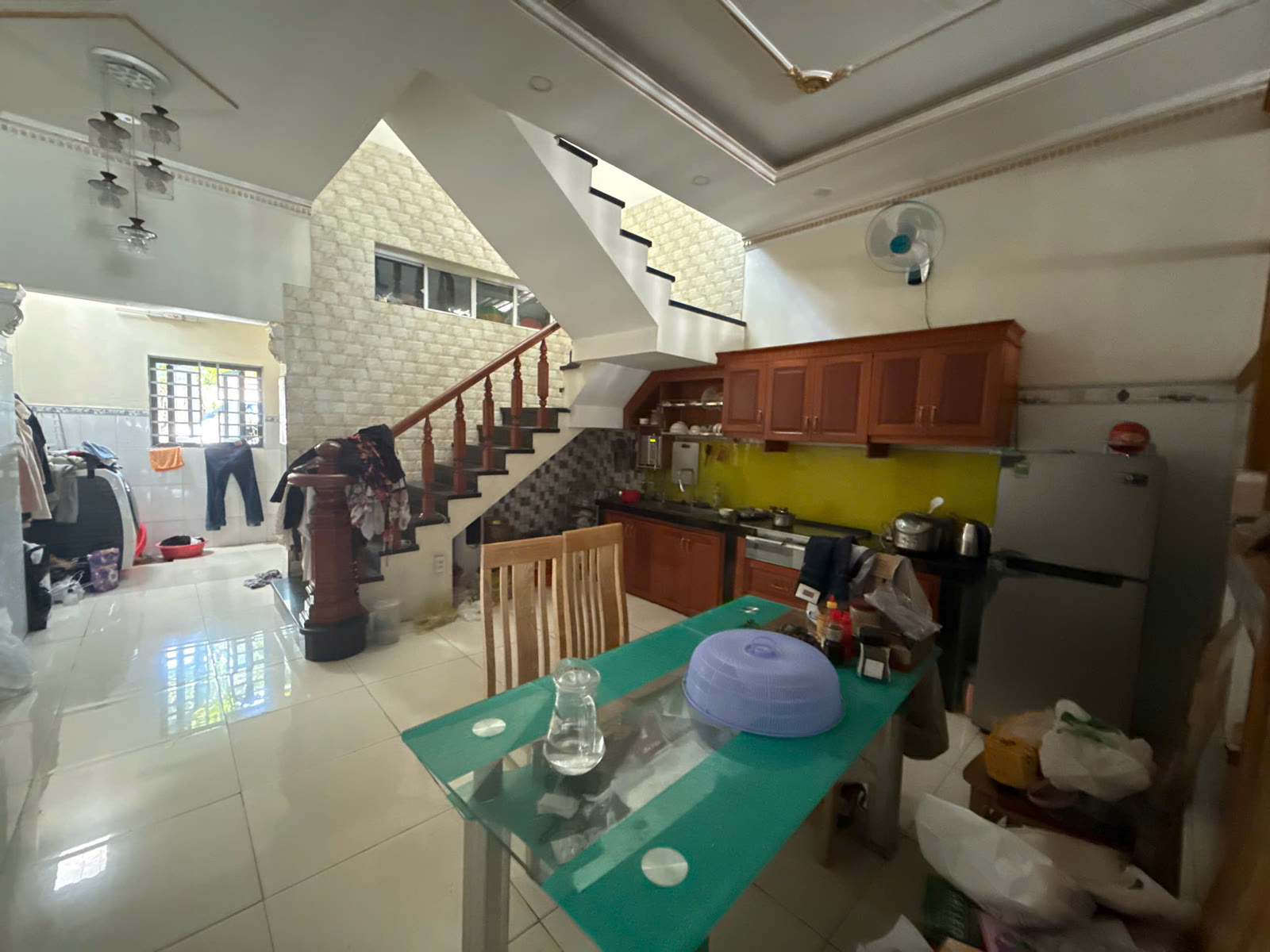 Bếp tầng trệt có tủ bếp trên dưới, bàn ăn và cầu thang gỗ trong nhà mặt tiền đối diện KCN Mỹ Phước 3