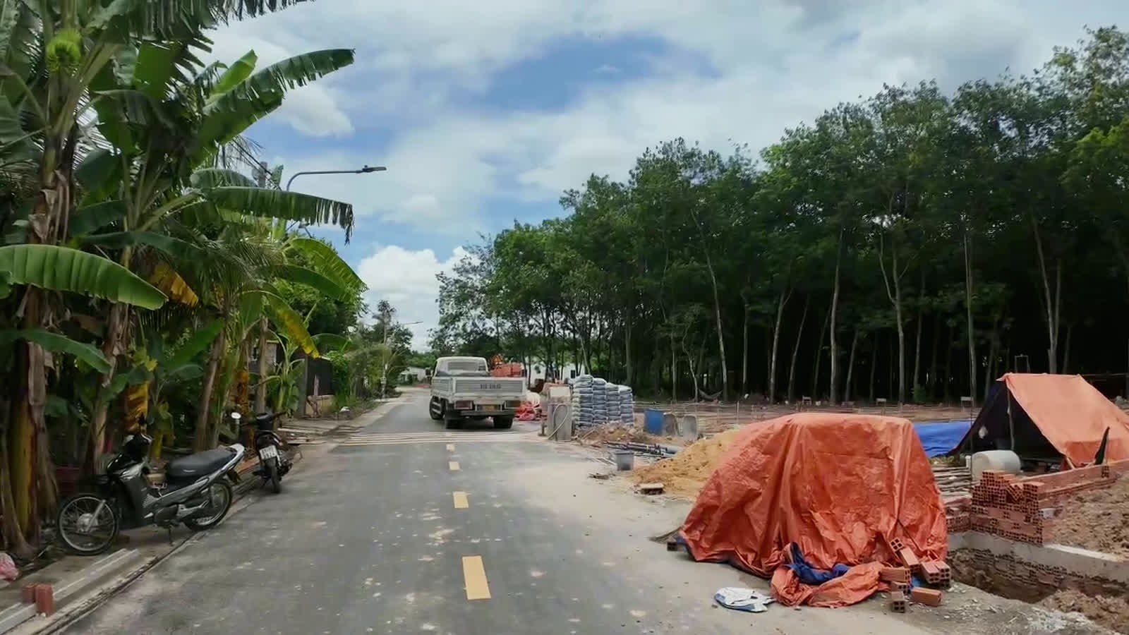 Nhà đang xây với gạch, cát tập kết dọc đường nhựa gần các lô đất sổ riêng ở Chánh Phú Hòa