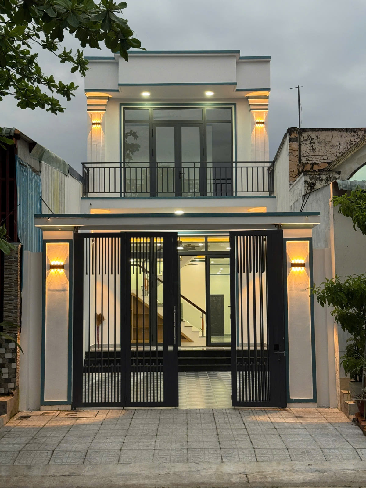 Mặt tiền nhà lầu trệt 5x20 khu tái định cư khu công nghiệp Mỹ Phước, cổng sắt 4 cánh và ban công tầng lầu