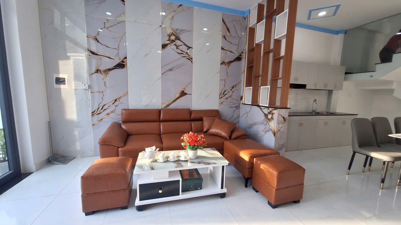 Phòng khách nhà lầu trệt Mỹ Phước 3 với bộ sofa da được tặng kèm và vách ốp giả đá