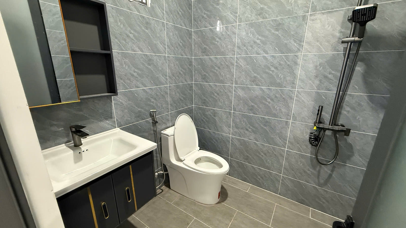 Toilet khép kín trong phòng ngủ tầng trệt có vòi tắm, bồn cầu và lavabo
